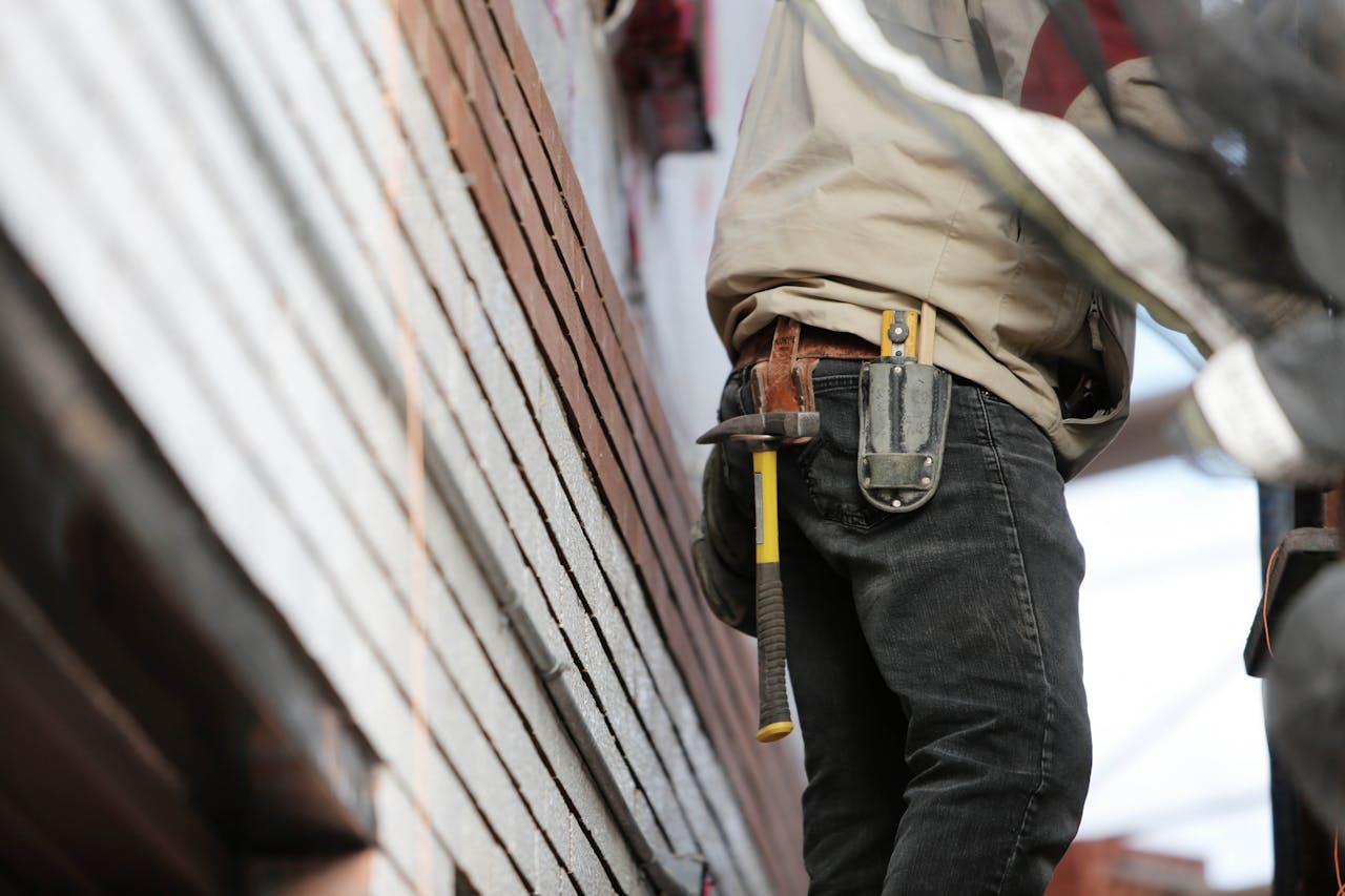 about-01 Close-up of a construction worker with hammer and tools, focused on the job.