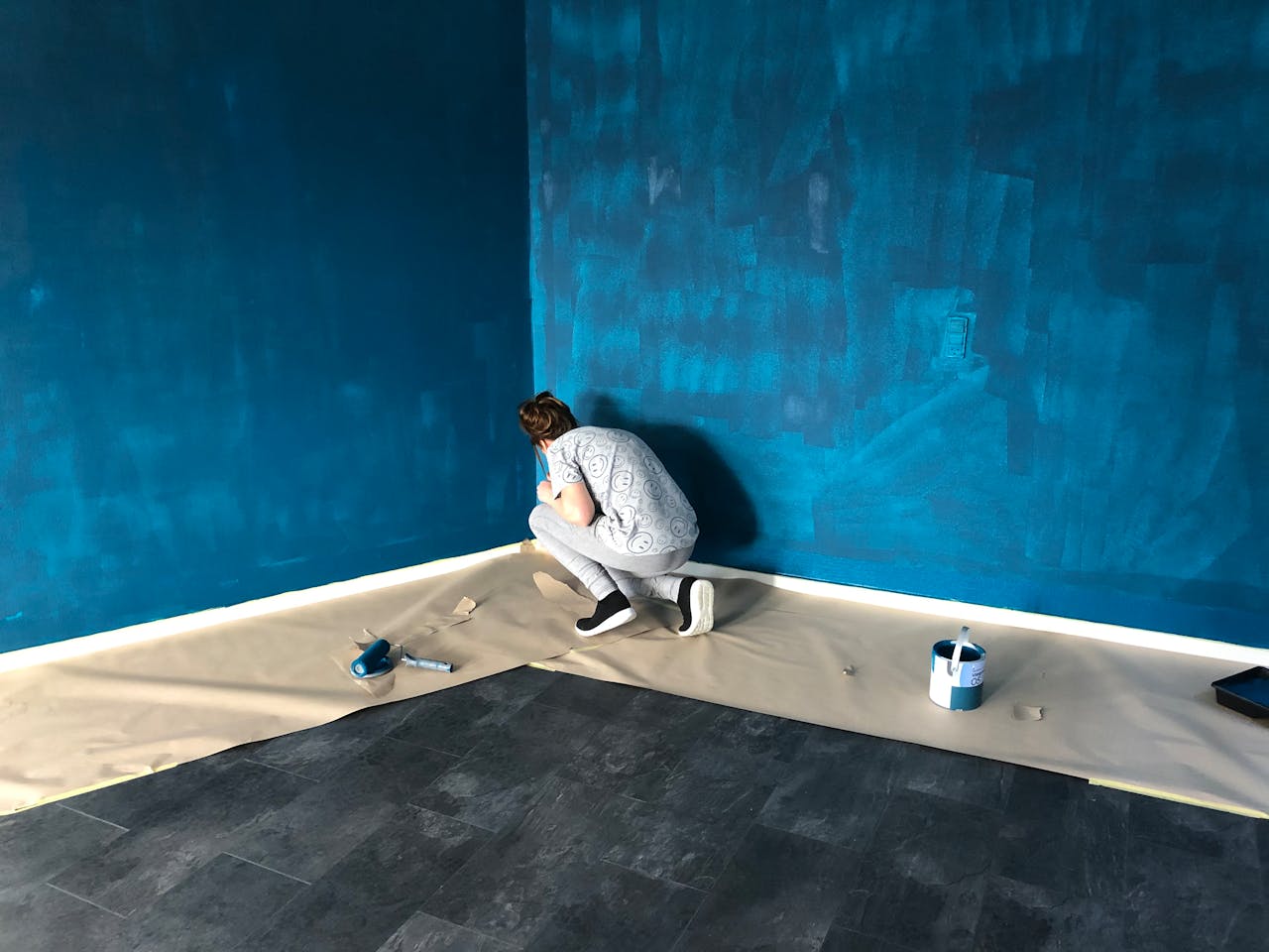 services-07 A woman painting a blue wall indoors for a home renovation project.